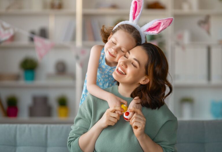 mãe e filha utilizando adereços de Páscoa e se abraçando enquanto sorriem